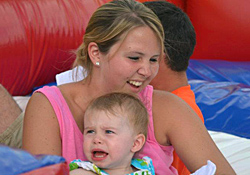 A woman and a small child sitting at the edge of a large red and blue inflatable
