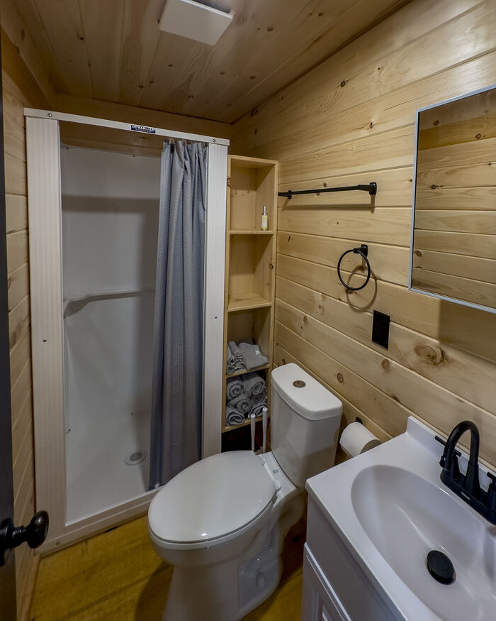 The bathroom with a shower stall, toilet, sink and folded towels