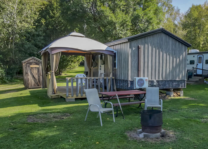 The cabin with its gazebo, deck, picnic table and fire ring on the lawn