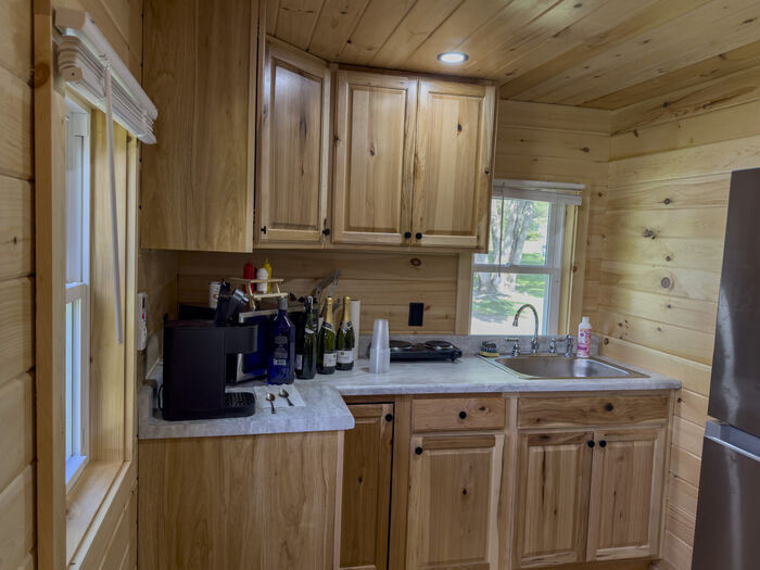 The kitchen counter with the sink, coffee maker and hot plate under pine cabinets