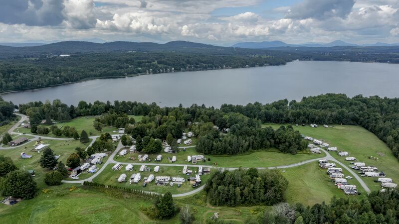 Aerial view across the campground toward a long lake ringed by wooded hills