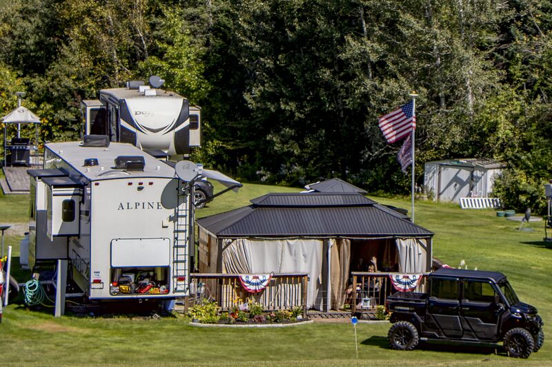 A seasonal site with a hard-topped gazebo, a flag and a side-by-side parked alongside
