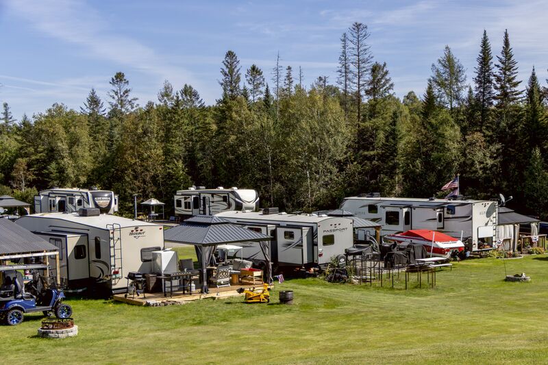 A row of seasonal campers backed against the spruce treeline