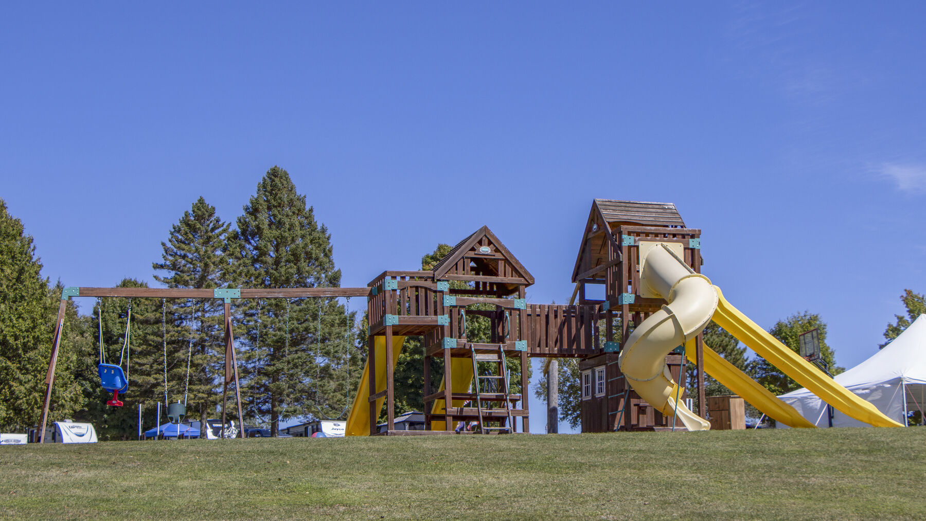 The campground playground, with swings, climbing frames and a spiral slide on the open lawn