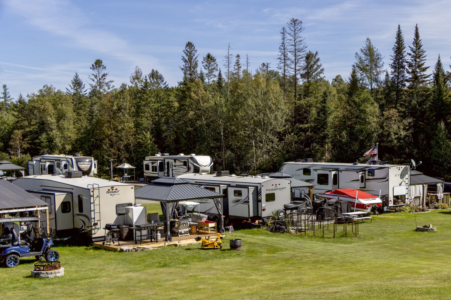 A row of seasonal campers along the treeline at the top of the campground