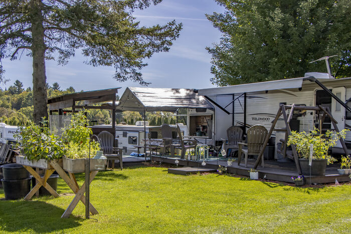 A shaded campsite with a long awning, planters and a wooden deck