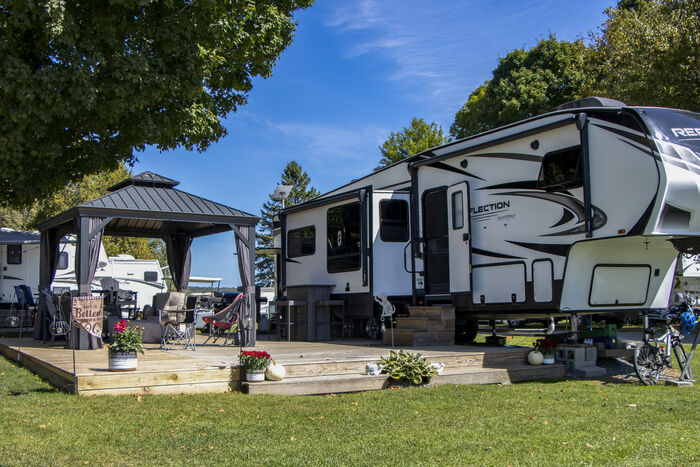 A fifth-wheel with a hardtop gazebo and a raised wooden deck