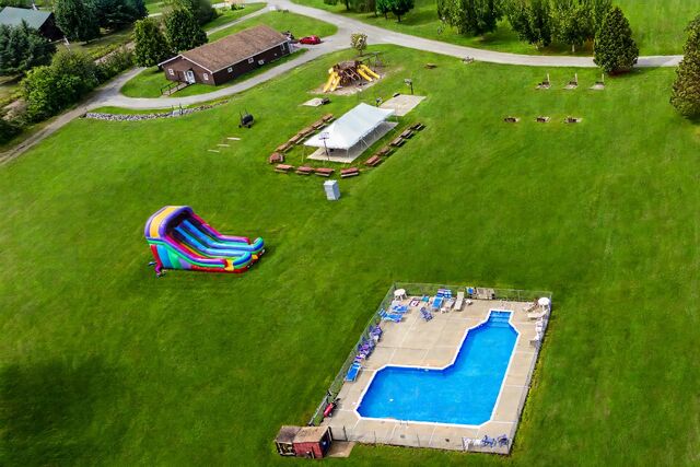 Aerial view of the in-ground swimming pool, the lawn, an inflatable slide and the playground